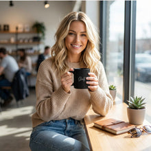 Load image into Gallery viewer, Woman holding a black mug with a golf logo in a cafe setting